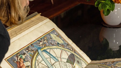 Librarian Rebecca Feakes studying the Harmonia macrocosmica Star Atlas by Andreas Cellarius
